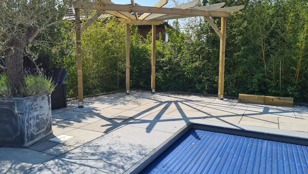 Paved area around swimming pool with pergola